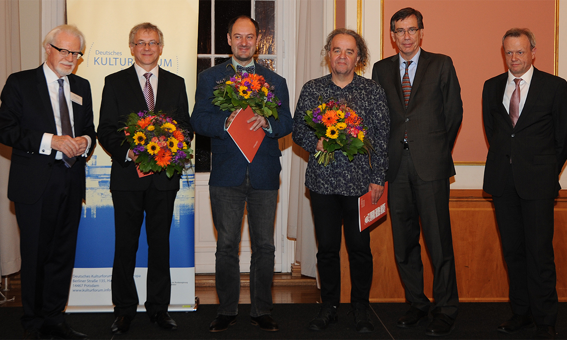 Die Georg Dehio-Buchpreisträger 2018 mit Blumen in der Hand von links: Alvydas Šlepikas, Markus Roduner und Miljenko Jergović. Brigitte Döbert fehlt krankheitsbedingt. Rechts daneben Dr. Günter Winands, BKM. Links außen Winfried Smaczny und ganz rechts Harald Roth vom Deutschen Kulturforum östliches Europa.