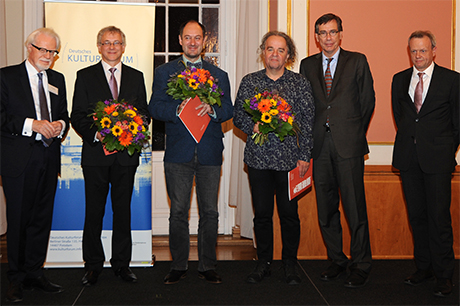 Die Georg Dehio-Buchpreisträger 2018 mit Blumen in der Hand von links: Alvydas Šlepikas, Markus Roduner und Miljenko Jergović. Brigitte Döbert fehlt krankheitsbedingt. Rechts daneben Dr. Günter Winands, BKM. Links außen Winfried Smaczny und ganz rechts Harald Roth vom Deutschen Kulturforum östliches Europa.